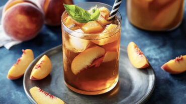 Photo of a peach iced tea recipe in a glass with a straw.