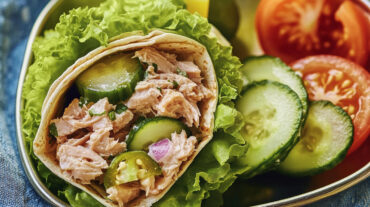 A photo of a tuna wrap with cucumber and lettuce.